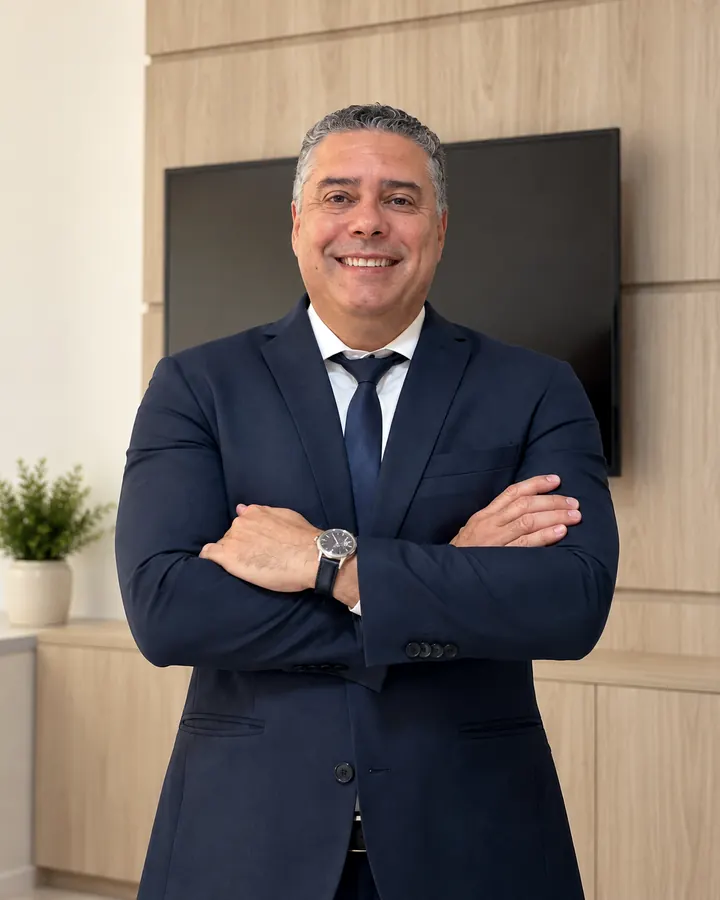 Dr. Rubem Ribeiro Neto, advogado, de terno azul-marinho e braços cruzados no escritório